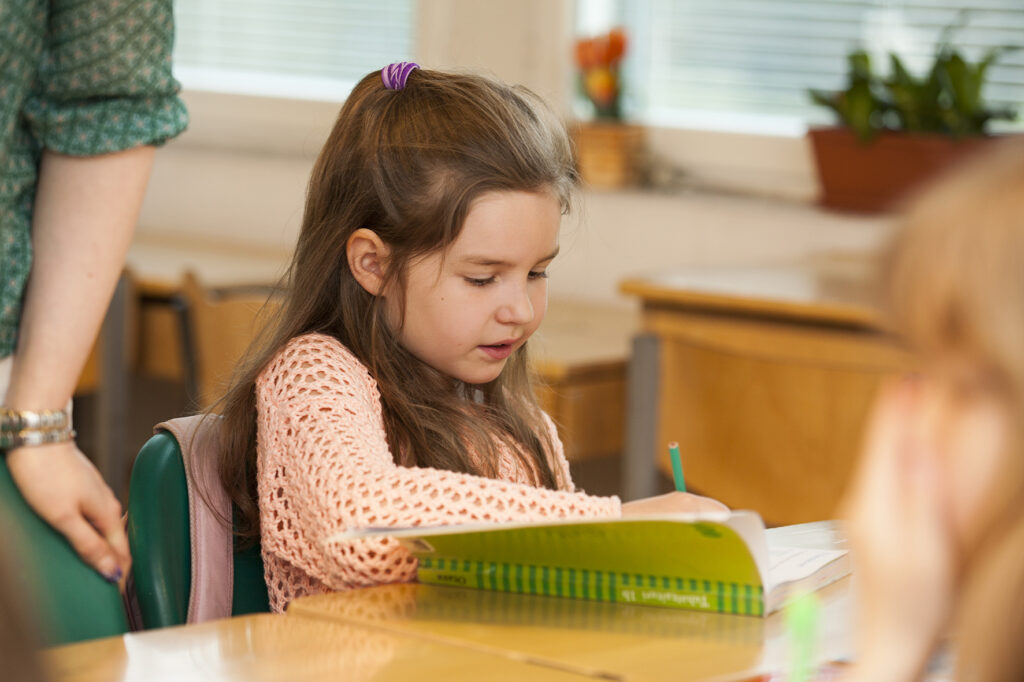 A schoolchild learning with the teacher's guidance.