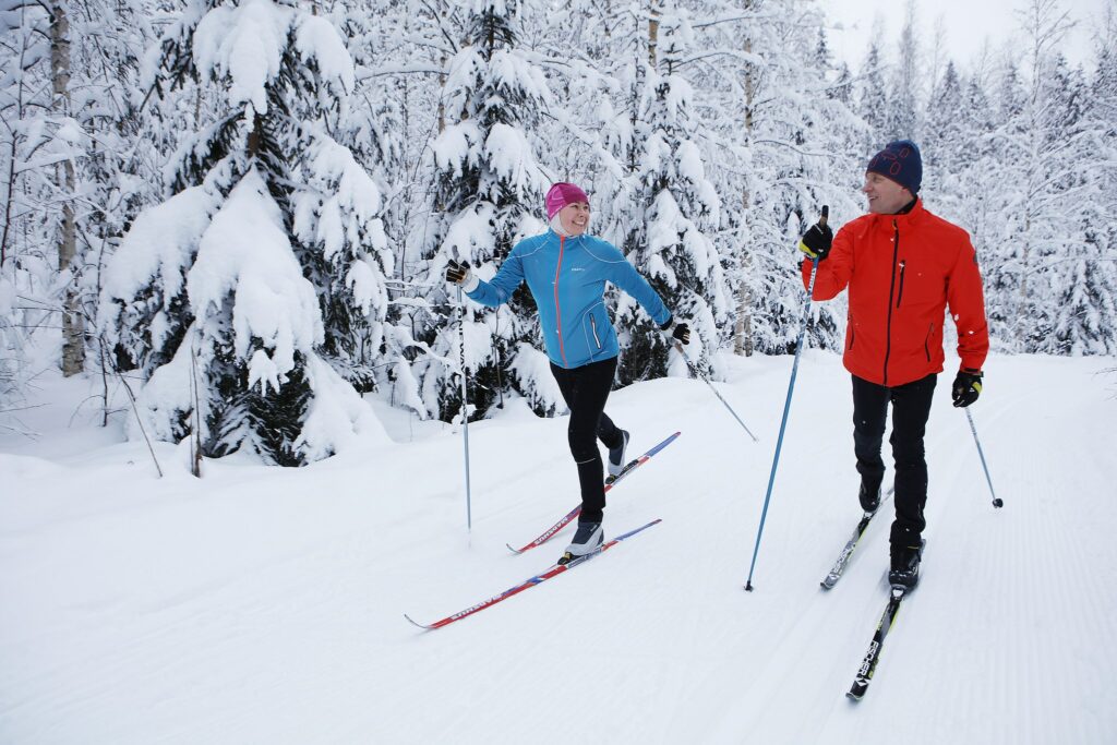 Två skidåkare friskt på en skidbacke i en vinterskog,