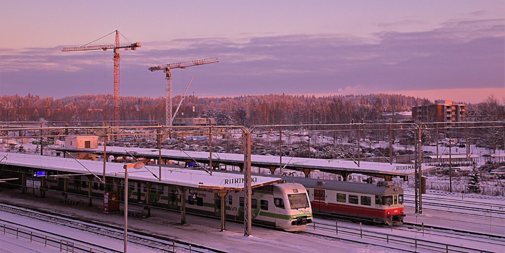 Riihimäen ruatatieaseman junaraiteilla kaksi junaa. Talvi auringonnousun pinkkisävyisissä väreissä.