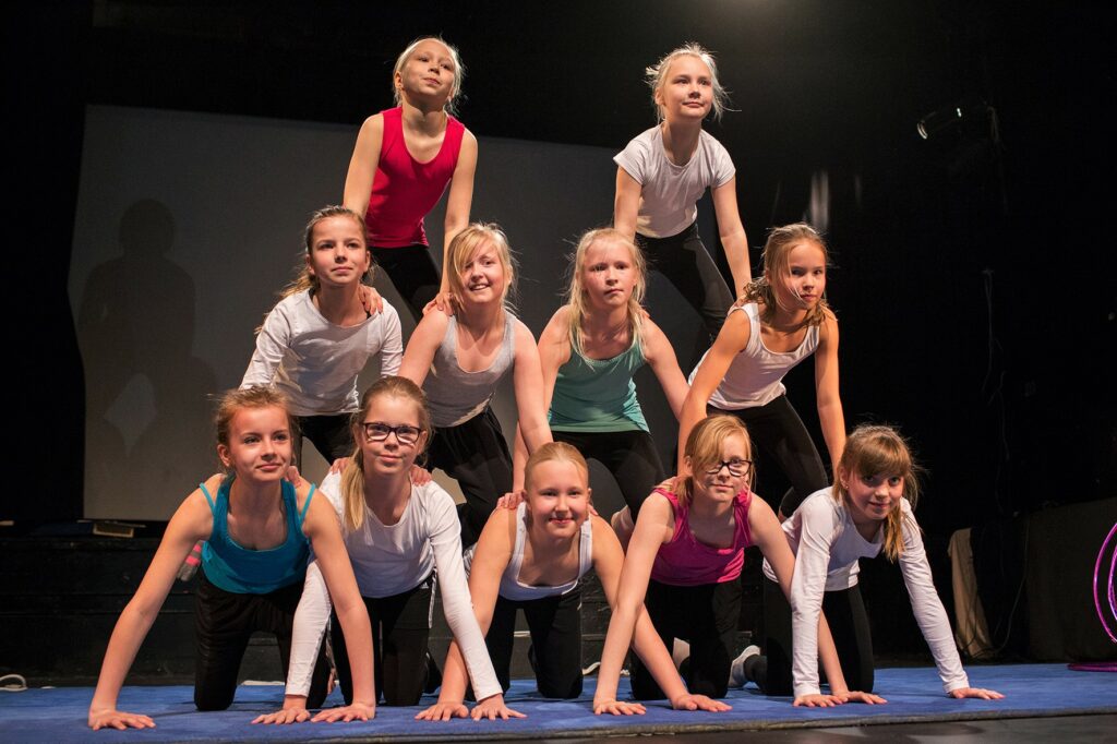 Nuorisoteatterin tytöt esittävät akrobatiaa. Ovat pyramidimuodostelmassa.
