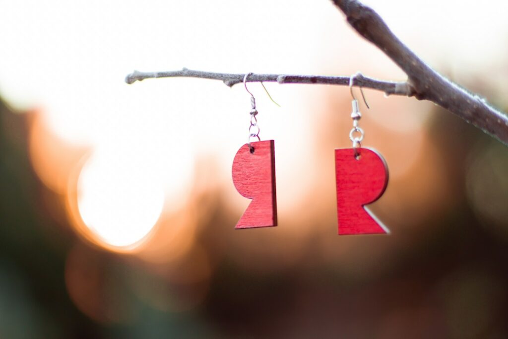 The earrings in the shape of the R symbol hang on a tree branch