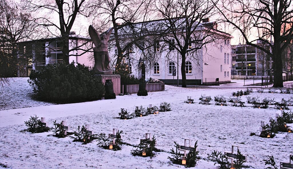 Talvinen näkymä itsenäisyydenpuiston sankarihautausmaalle. Taustalla näkyy valkoinen rakennus.