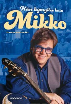 Kansikuva Tuomas Marjamäen kirjasta Hän hymyilee kuin Mikko. Kuvassa hymyilevä Mikko Alatalo kitaran kanssa.