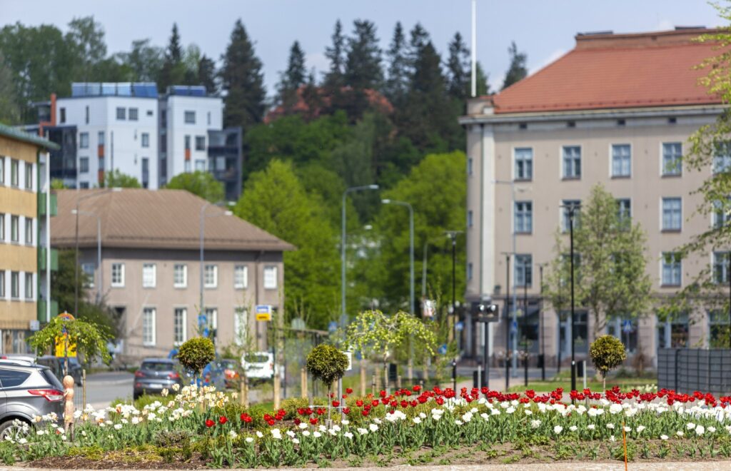 Etualalla liikenneympyrä kukkaistutuksineen, taustalla kerrostaloja.