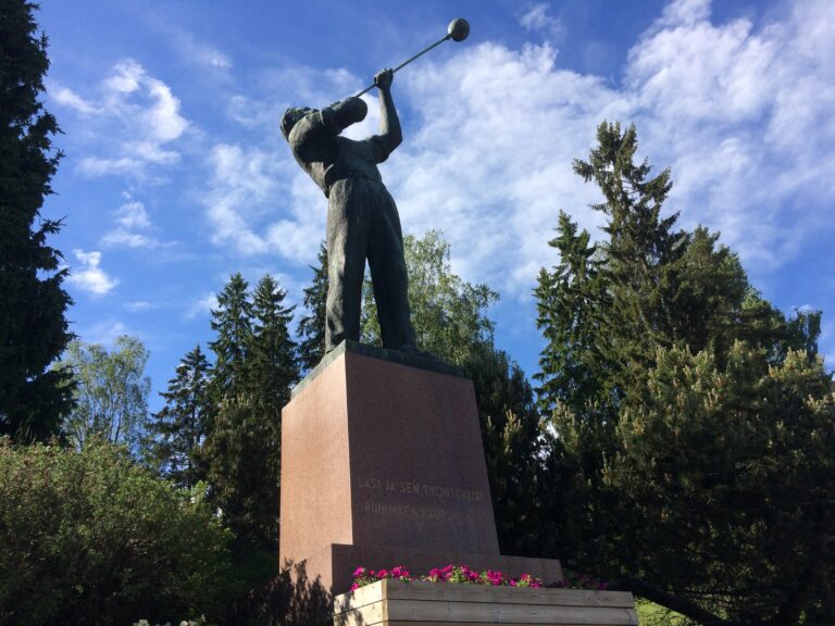 A statue of a glassblower and a forest in the background.