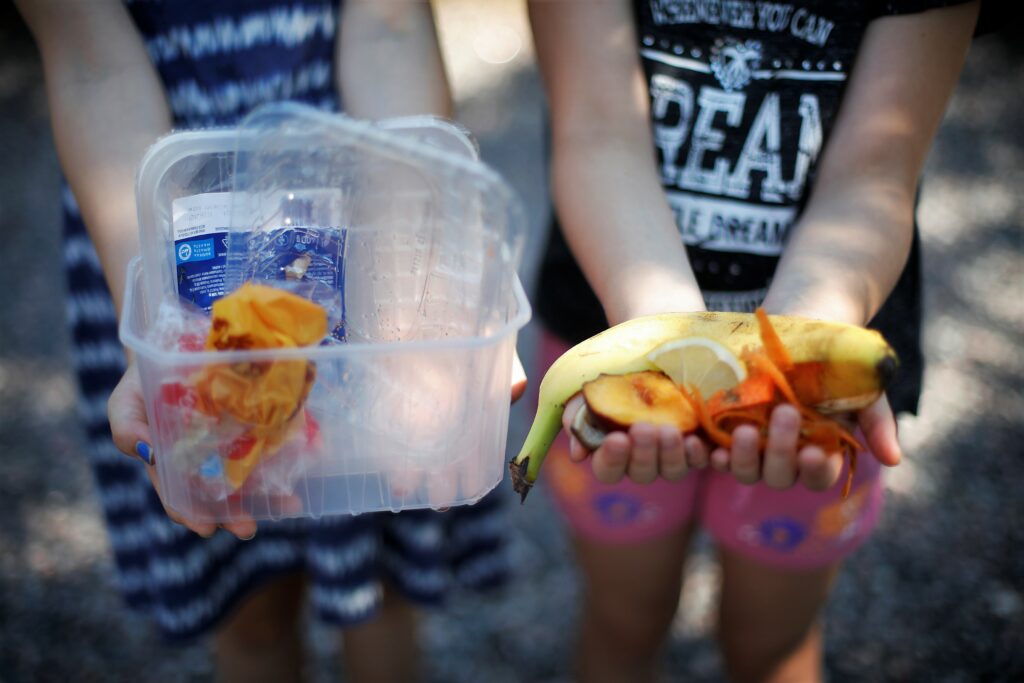 In the close-up, two children are holding plastic and organic waste.