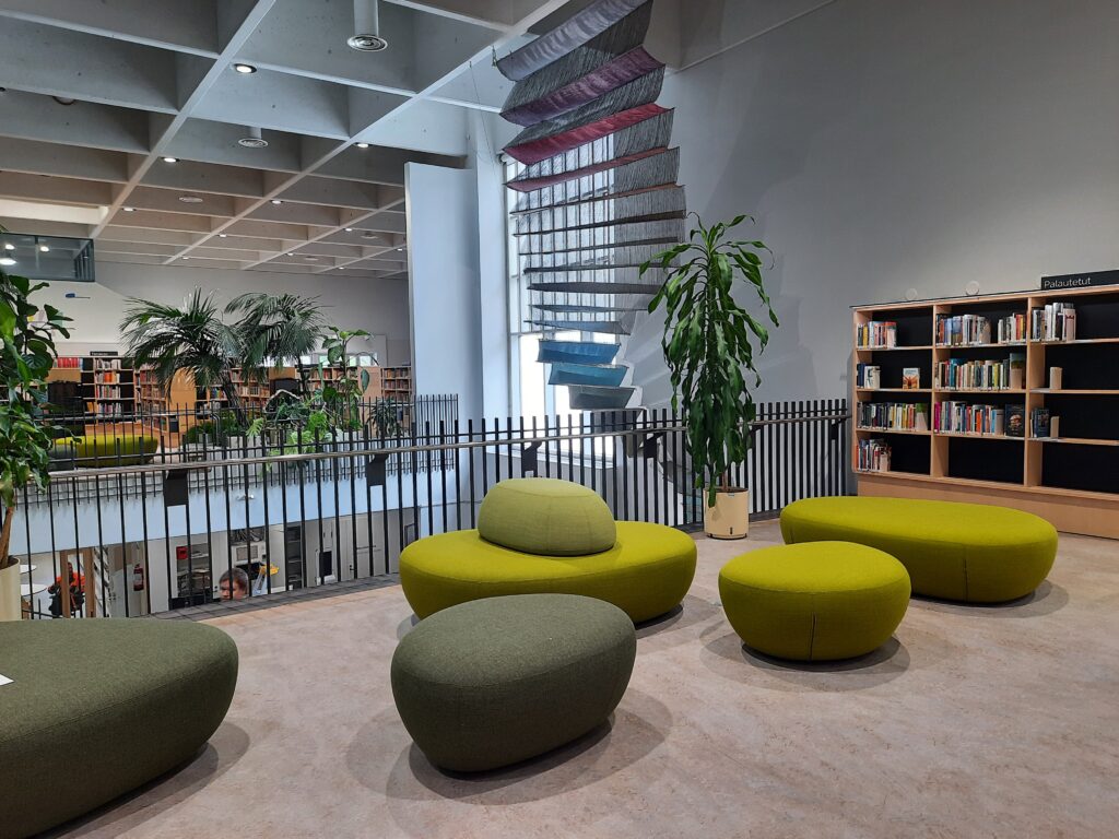 Sisäkuva kirjastosta, hyllyjä ja tuoleja.
