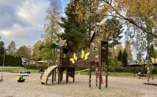 Kuvassa Perhospuison perhosilla koristeltu puinen kiipeilyteline, jossa lapsia leikkimässä.