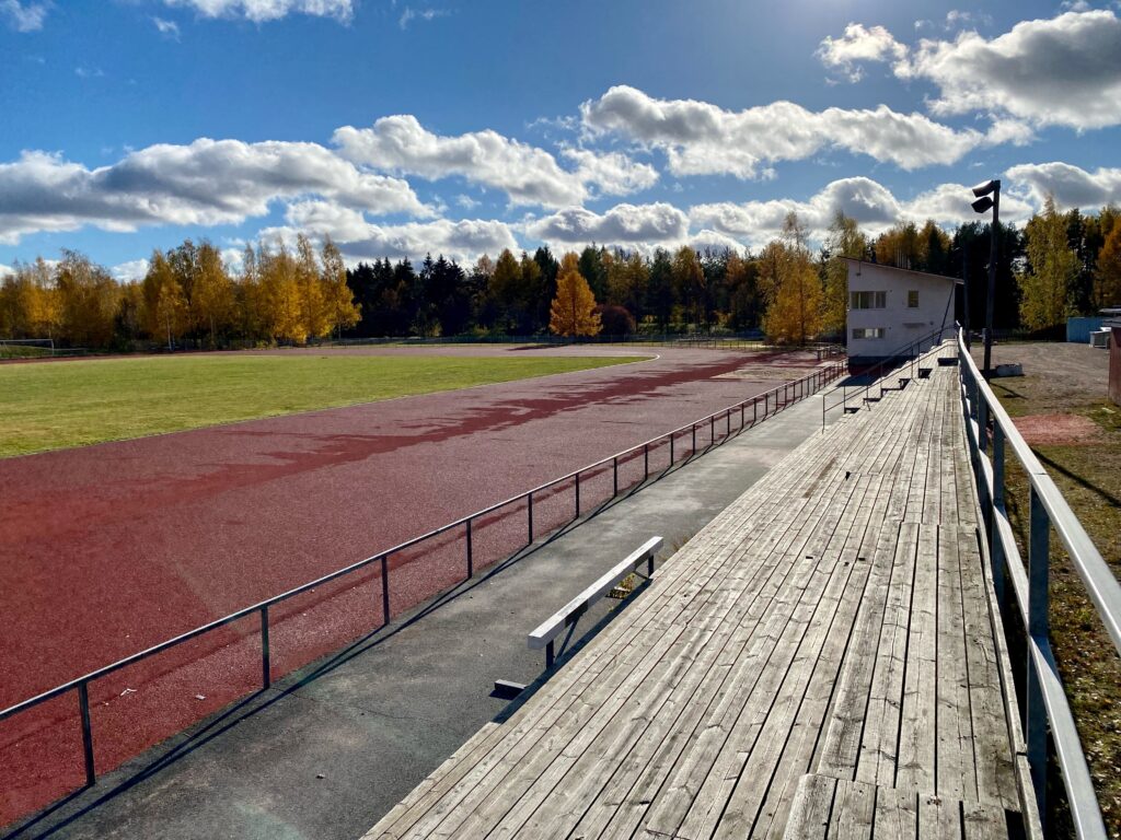 Näkymä Peltosaaren yleisurheilukentälle katsomosta käsin. Etualalla katso, jonka päässä valvontakoppi.