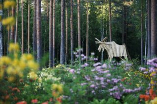 Atsaleoja puiden keskellä ja laudoista rakennettu iso hirvi atsaleapuistossa.