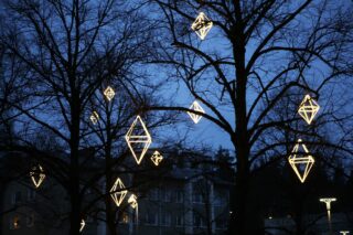 The trees in Kolmiopuisto have himmel-shaped lights that shine against the dark blue night sky.