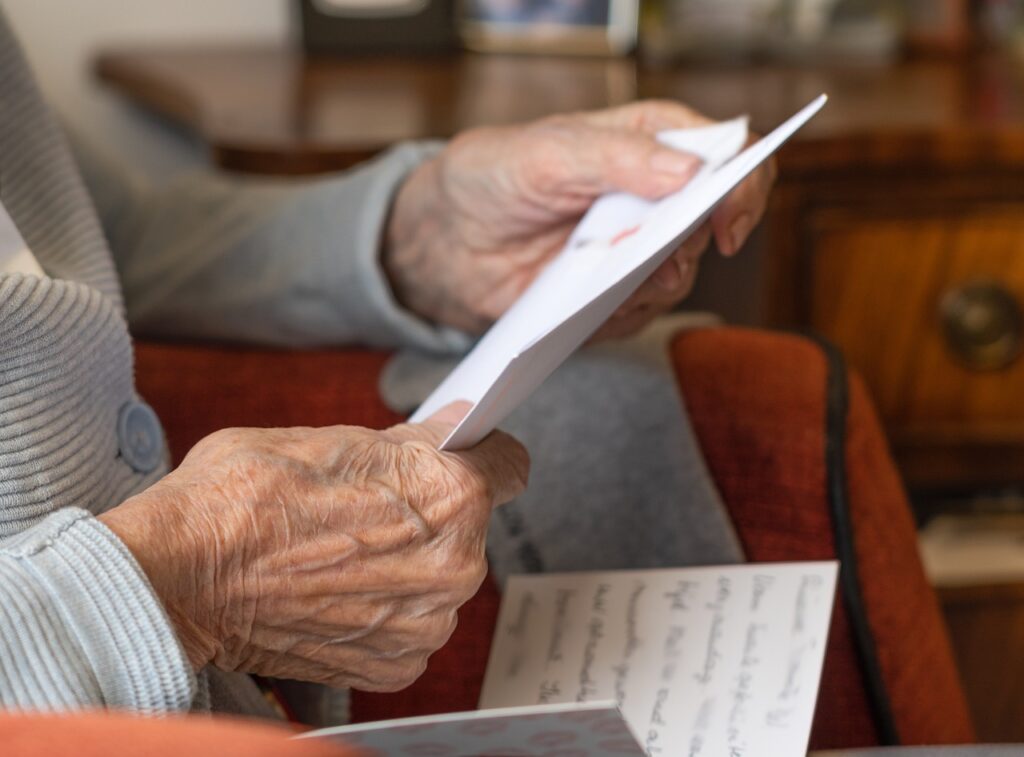 Vanhuksen kädet pitelevät avattua kirjettä.