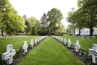 Hjältens kyrkogård i Insenäisyydenpuisto är fotograferad från mellan gravarna mot hjältens staty.