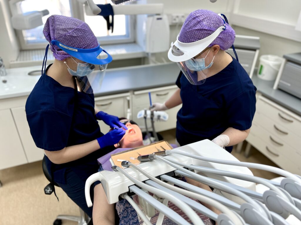Hammaslääkäri ja hammashoitaja hoitavat potilaan hampaita.