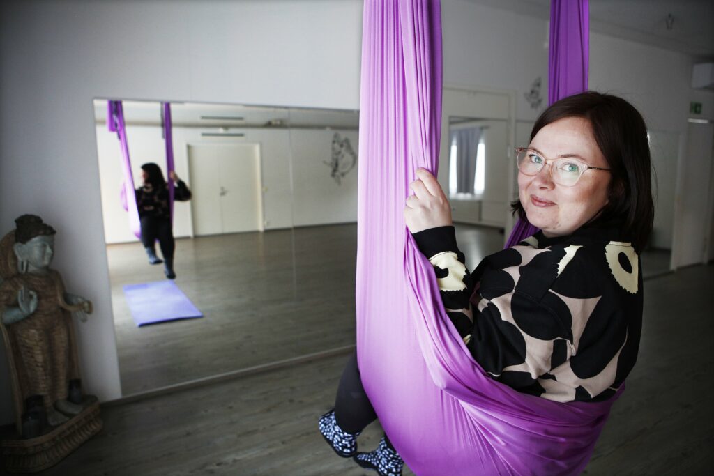 Silla Kakkola sitting in an aerial yoga mat in the yoga hall.