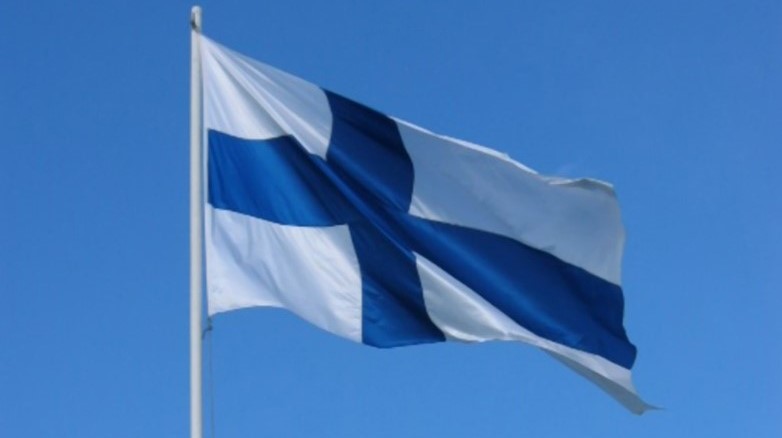 Suomen lippu liehumassa vaaleansinistä taivasta vasten.