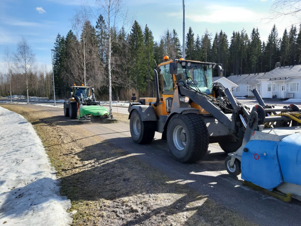 Kaksi hiekanpoistokonetta ajamassa tiellä.