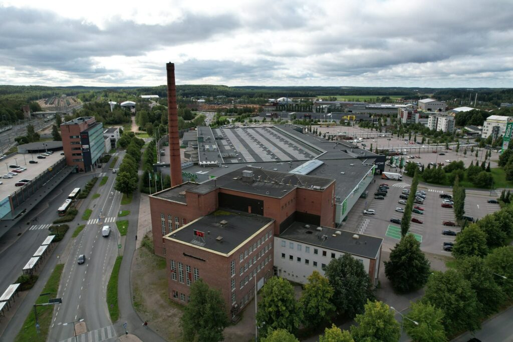 The brick Voimala building with chimney. Next to the Atomi shopping center and the railway.