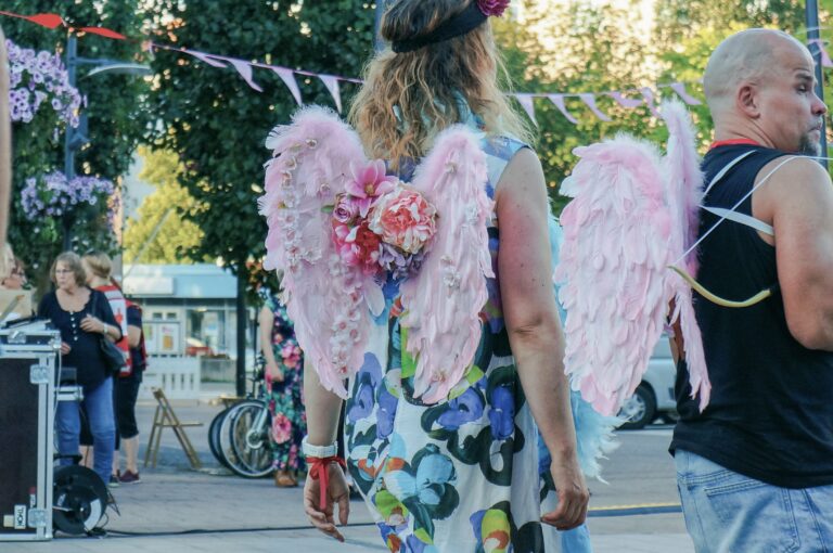 Two people wearing pink wings with flowers.