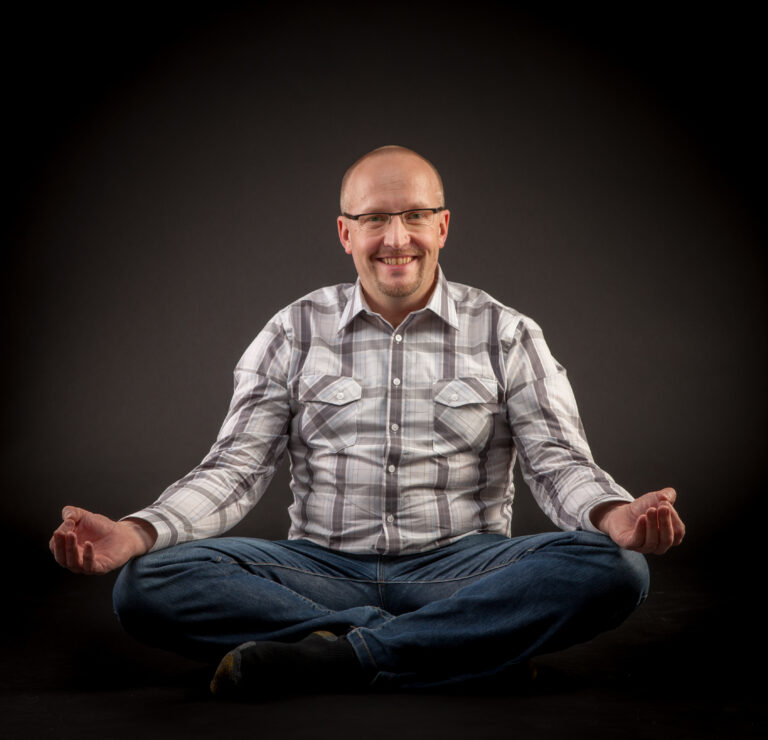 A person sits in the lotus position and smiles.