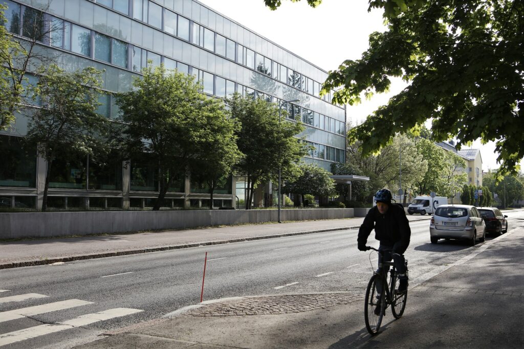 Etualalla pyöräilijä Kalevankadun kevyen liikenteen väylällä, taustalla Kalevantalo.