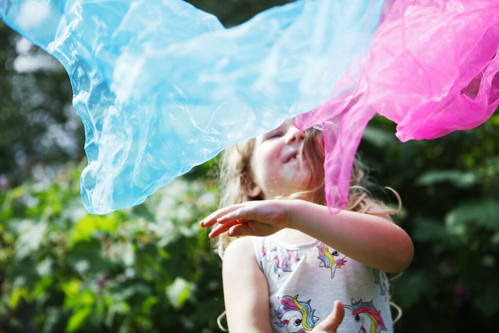 Lapsi, jonka edessä on kaksi eriväristä isoa saippuakuplaa.