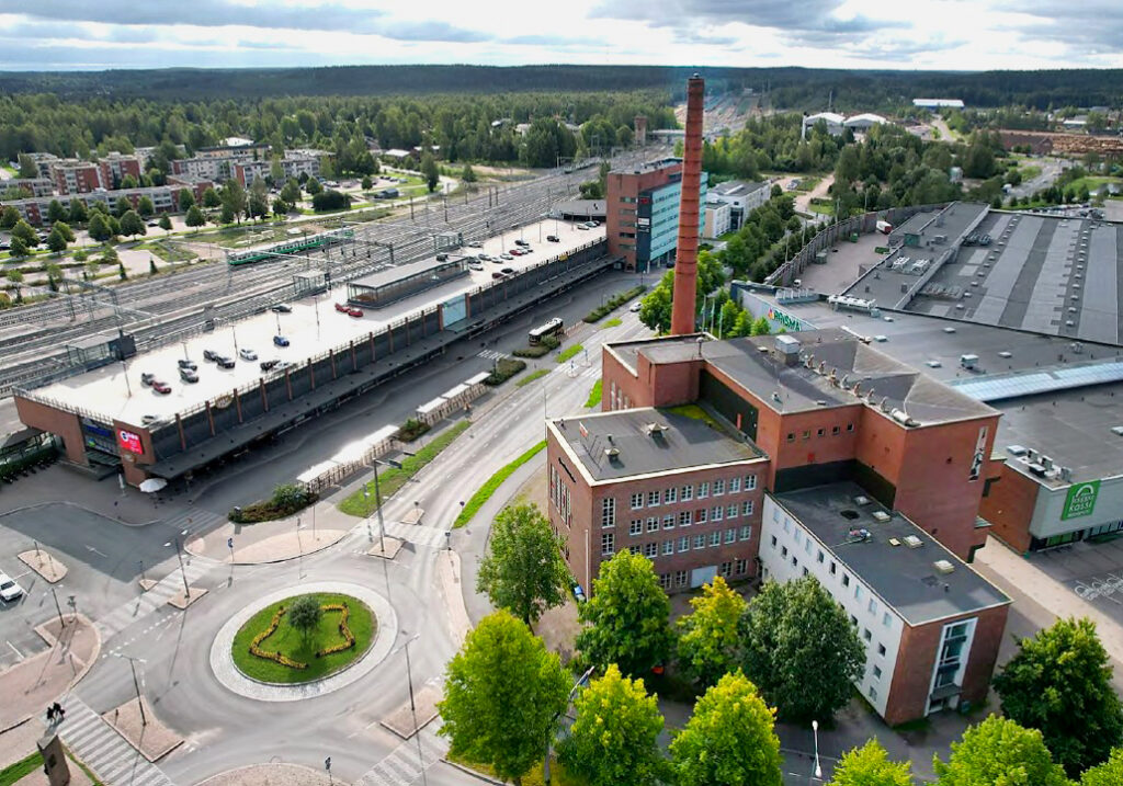 Punatiilinen voimalarakennus piippuineen edessä oikealla, Matkakeskus ja rautatie kuvassa vasemmalla.