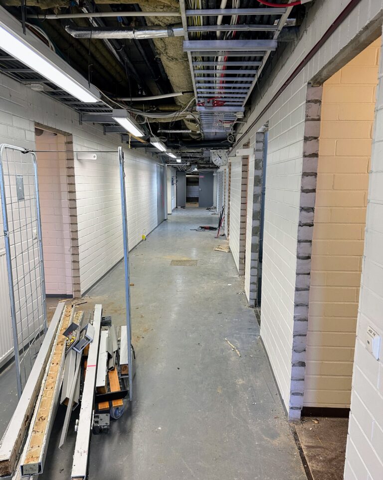 In the picture, the basement floor corridor of the Riihimäki swimming pool, where demolition work is in progress. In the foreground of the picture are disassembled door frames in a bundle..