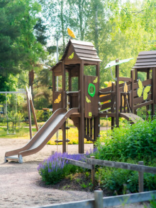 The climbing frame of the butterfly park, which also has a slide, is surrounded by vegetation and butterfly decorations according to the theme.