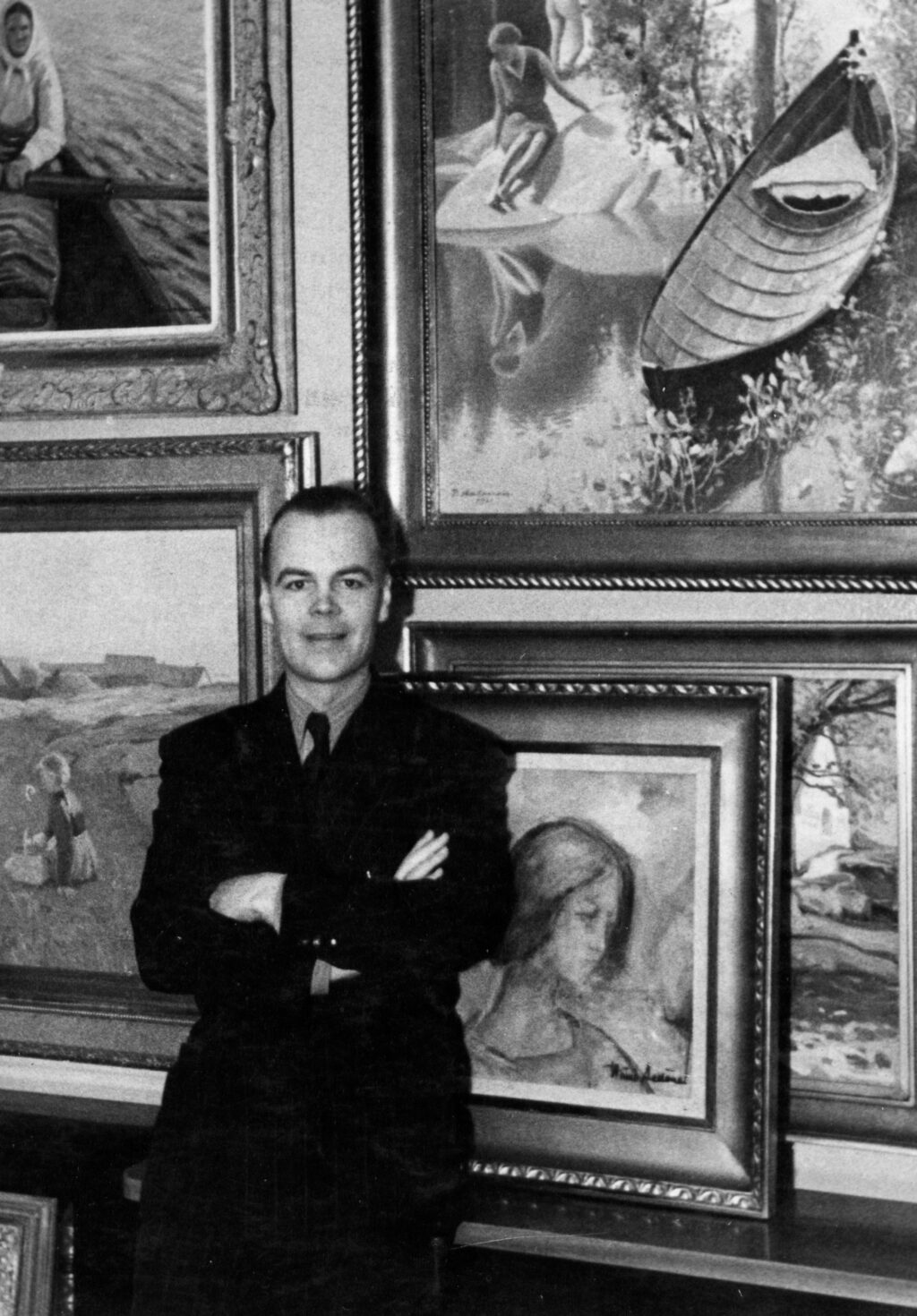 Mustavalkoinen kuva Pentti Wähäjärvestä seisomassa taidekokoelmaansa kuuluvien teosten äärellä.