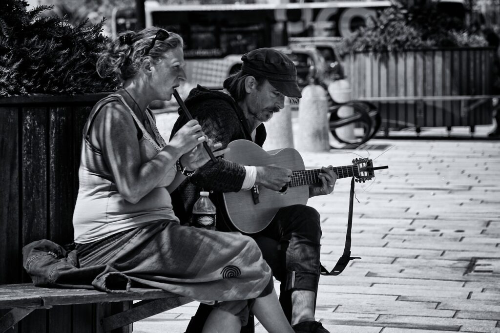 Puistonpenkillä mies soittaa kitaraa ja nainen huilua.