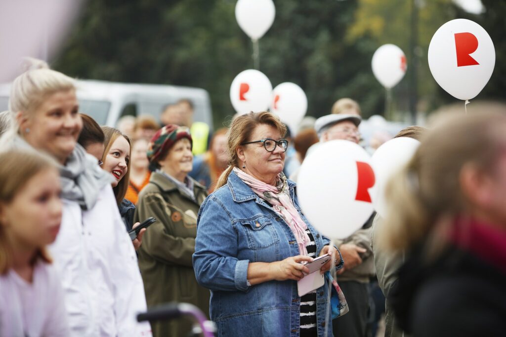 Riihimäki 60 vuotta -juhlan yleisöä Riihimäki-ilmapallojen kanssa ulkona seisomassa ja seuraamassa ohjelmaa.