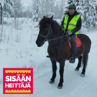 Talvivaatteisiin sonnustautunut henkilö tumman hevosen selässä talvimaisemassa. Henkilöllä on päällään myös heijastinliivi.