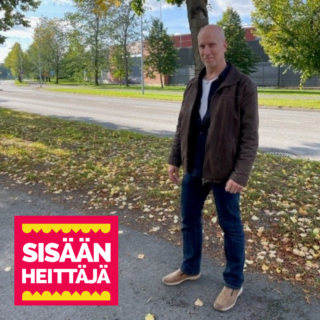 A bald-headed person with his jacket open looks at the camera with a determined expression on his face, in the background is the atmosphere of early autumn, the highway, leaves on the ground and the sun is shining.