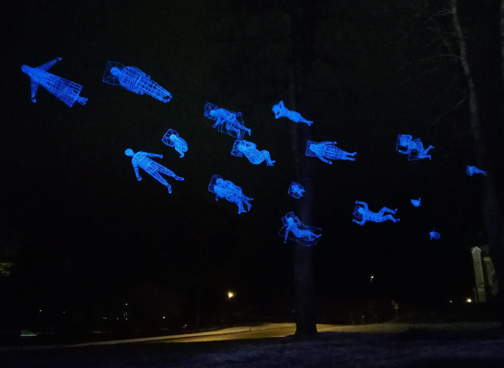 Pimeässä sinisenä loistavana lentäviä ihmishahmoja ilmassa.