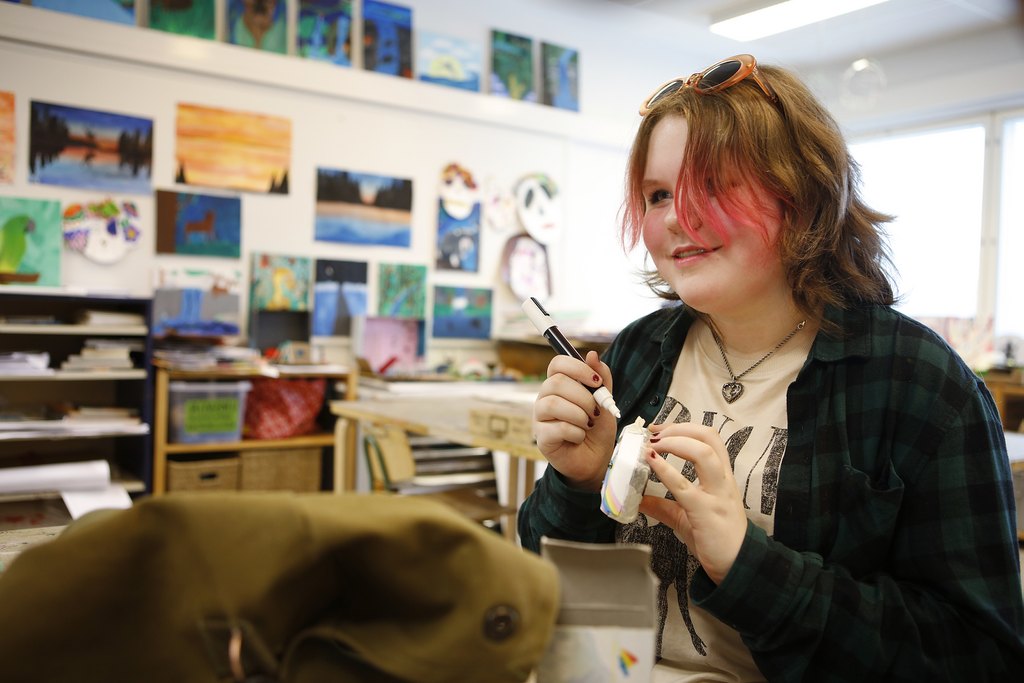 A young woman is sitting at a table in an art class.