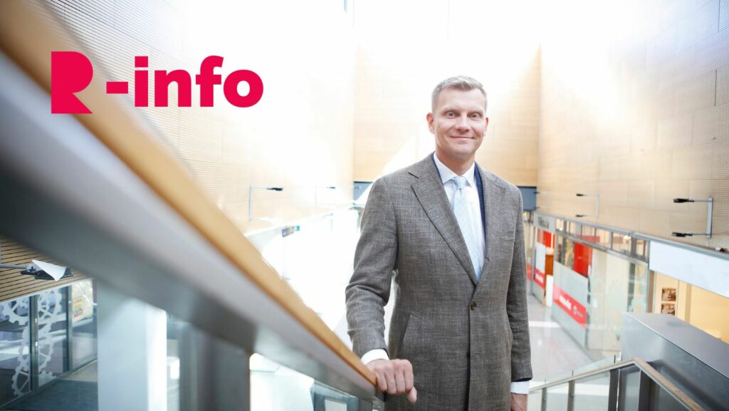 Smiling man in suit with hand on stair railing.