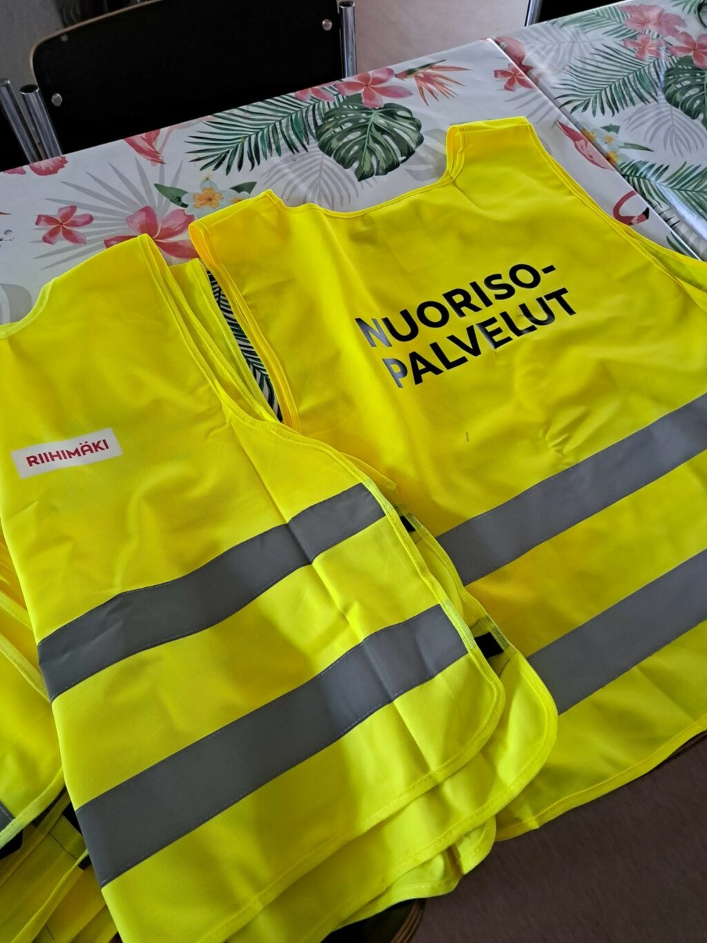 Kaksi neonkeltaista huomioliiviä pöydällä. Liivin selässä teksti Nuorisopalvelut.
