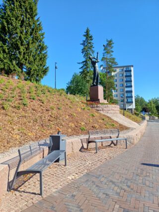 Lasinpuhaltajapatsas ja sen edustalla muurin vieressä sijaitsevat penkit