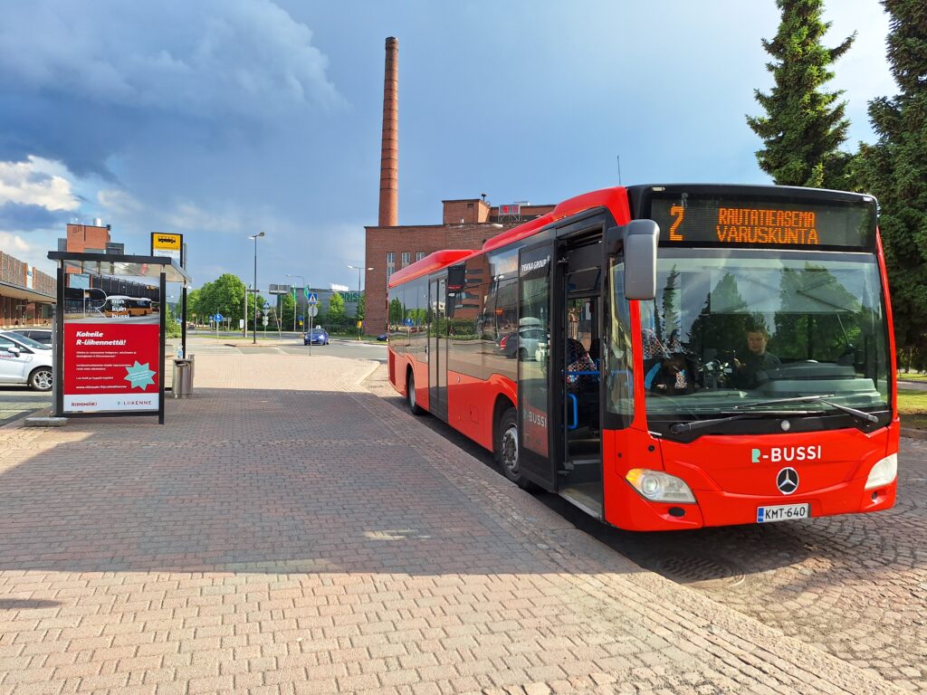 R-liikenteen punainen bussi seisoo pysäkillä.