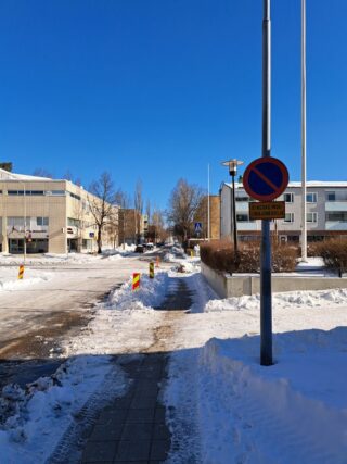 Luminen katunäkymä liikennemerkin kera, taustalla rakennuksia