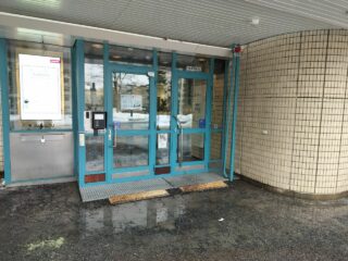 Asfalttipihalla rakennus ja kaksi ovea.