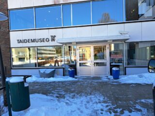 Kaksikerroksinen rakennus, jonne johtaa kahdet ovet. 
