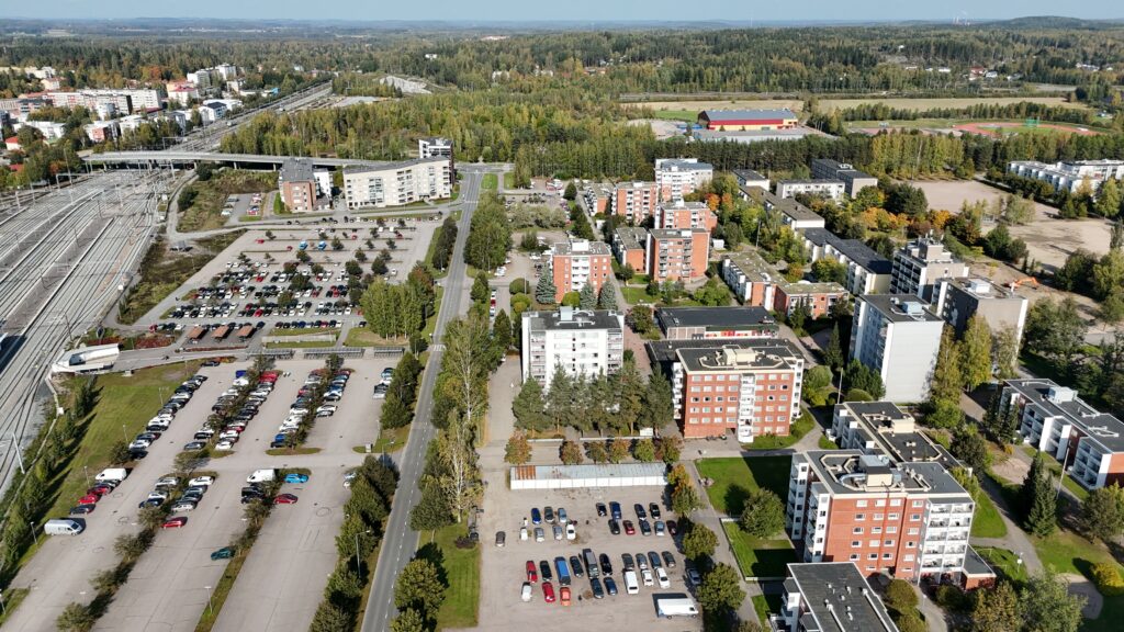 Ilmakuva kerrostalovaltaisestaasuinalueesta, joka on rautatieraiteiden vieressä.