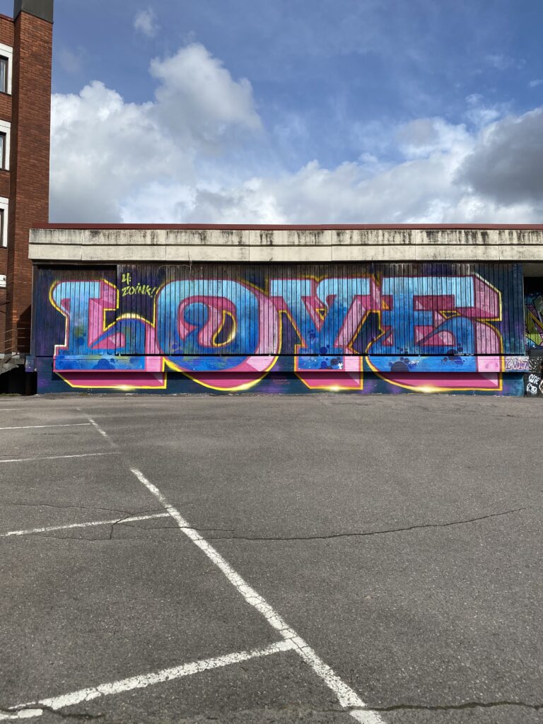 Parkkialueella rakennukseen maalattu graffititaideteos, jossa lukee "love"
