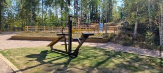 Etualalla kehonpainokuntoiluväline ja taaempana kunttaluiskan takana puinen kiipeilyväline.
