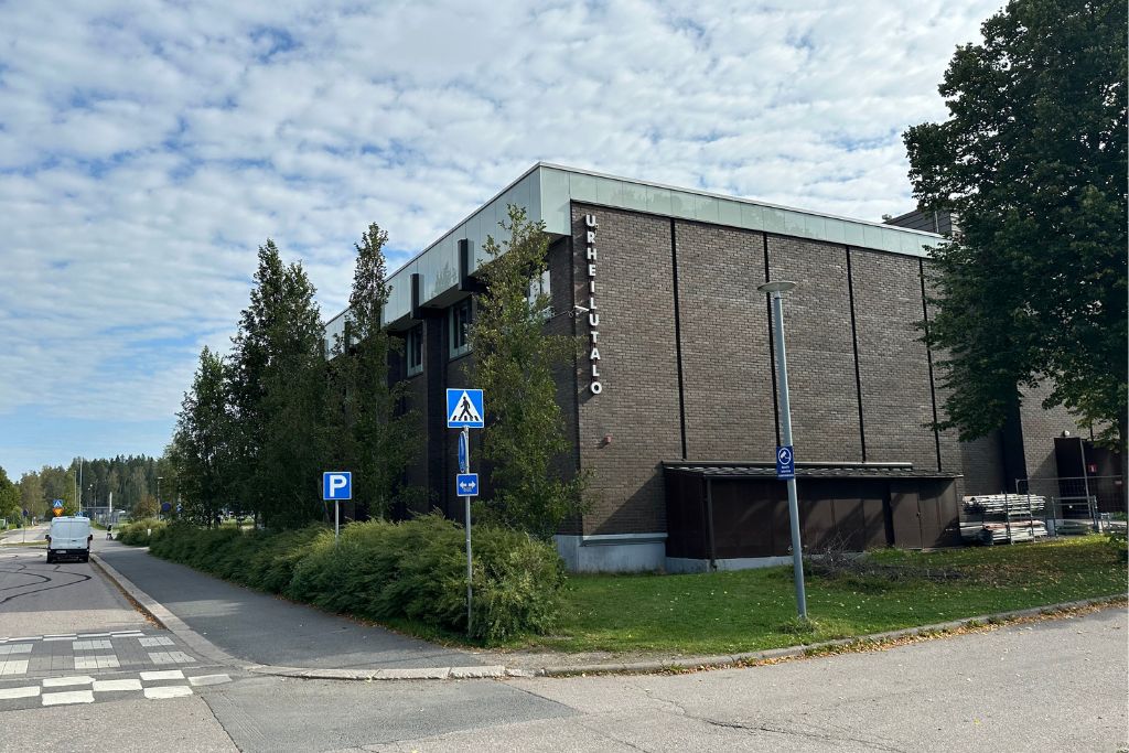 Tasakattoinen iso rakennus tien kulmauksessa.