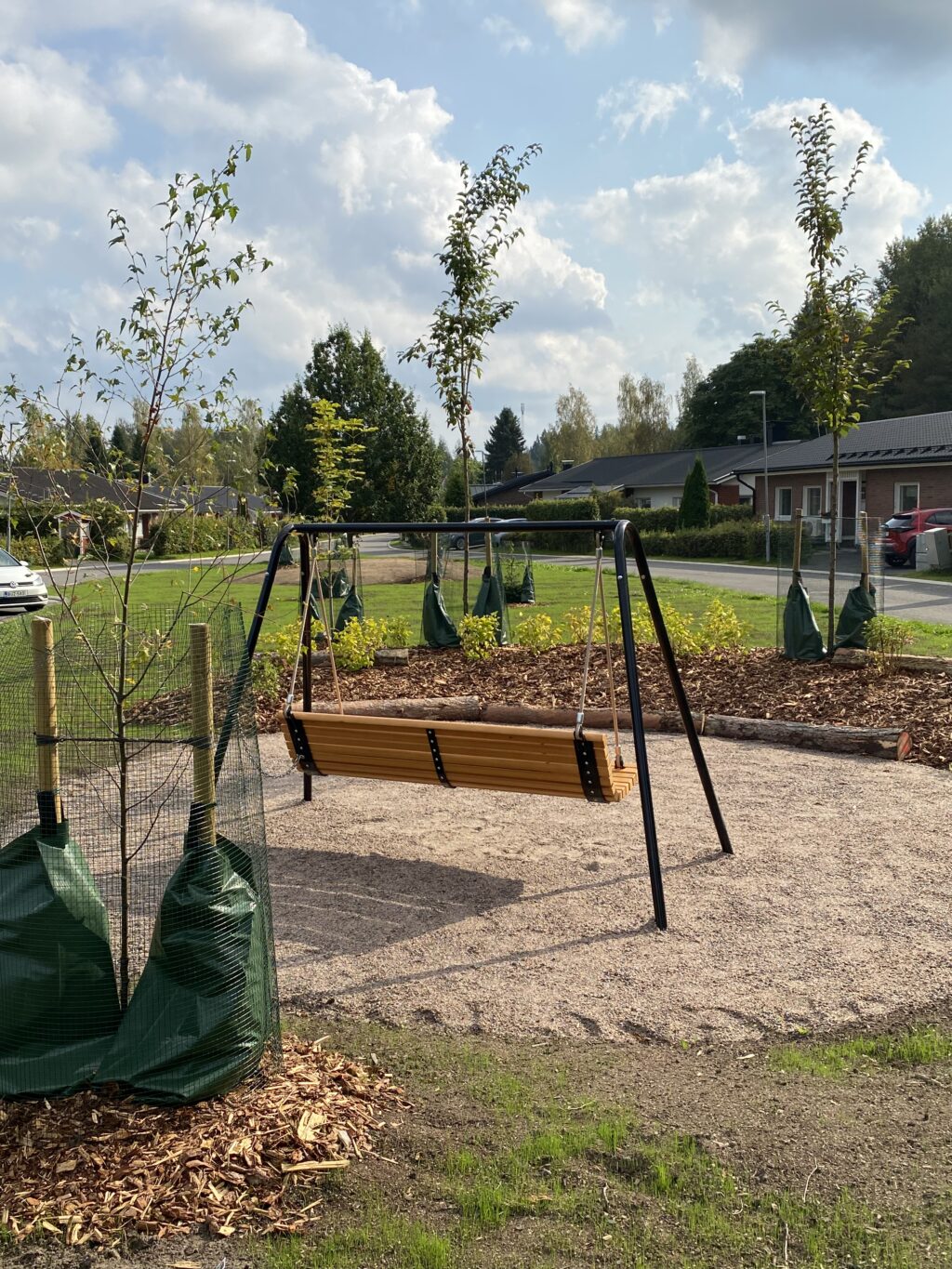 Maisemoidulta viheralueelta löytyy puutarhakeinu ja lahopuilla reunustettu istutusalue.