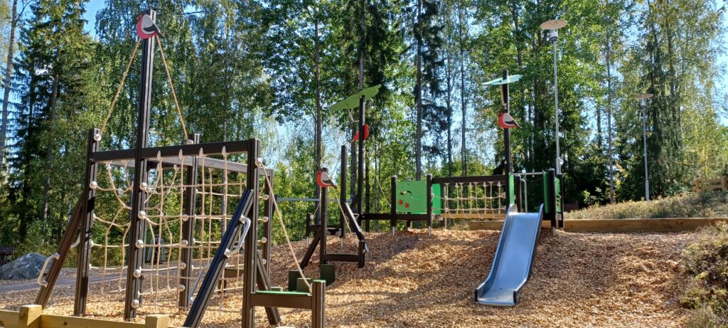 Savottapuiston puinen kiertorata kiipeilyteline, jossa välineen mastoissa on isoja punatulkkuja.