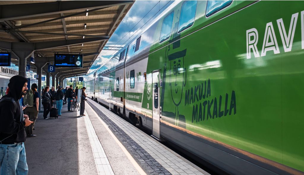 Uudenaikainen Intercity-juna ja sen ravintolavaunu pysähtyneenä juna-aseman laiturille. Vaalean taivas ja ihmisiä laiturilla.